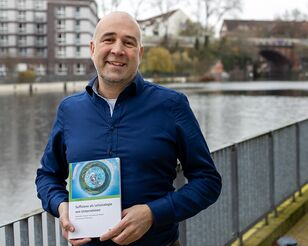 Portrait André Jäger mit Fachbuch in der Hand